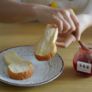 A person spreading strawberry jam on bread slices. Perfect breakfast concept.