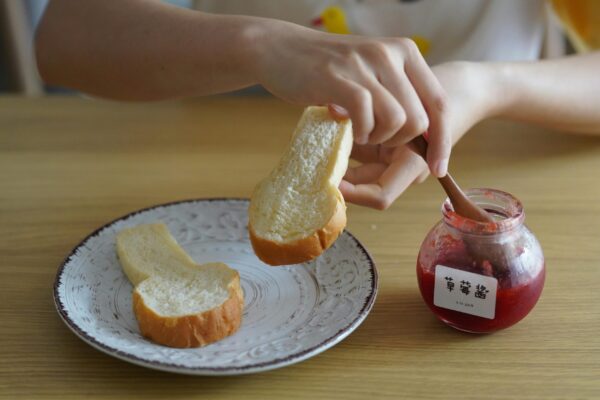 A person spreading strawberry jam on bread slices. Perfect breakfast concept.